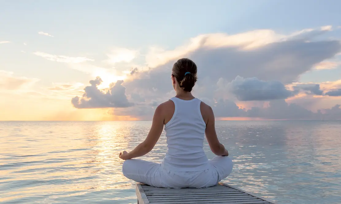 woman at edge of dock lotus position